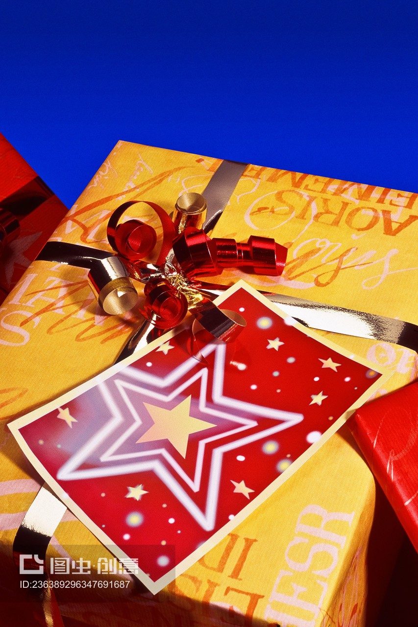 gold metallic bow with ribbon curl tied around gift and Christmas present star on red card blue background